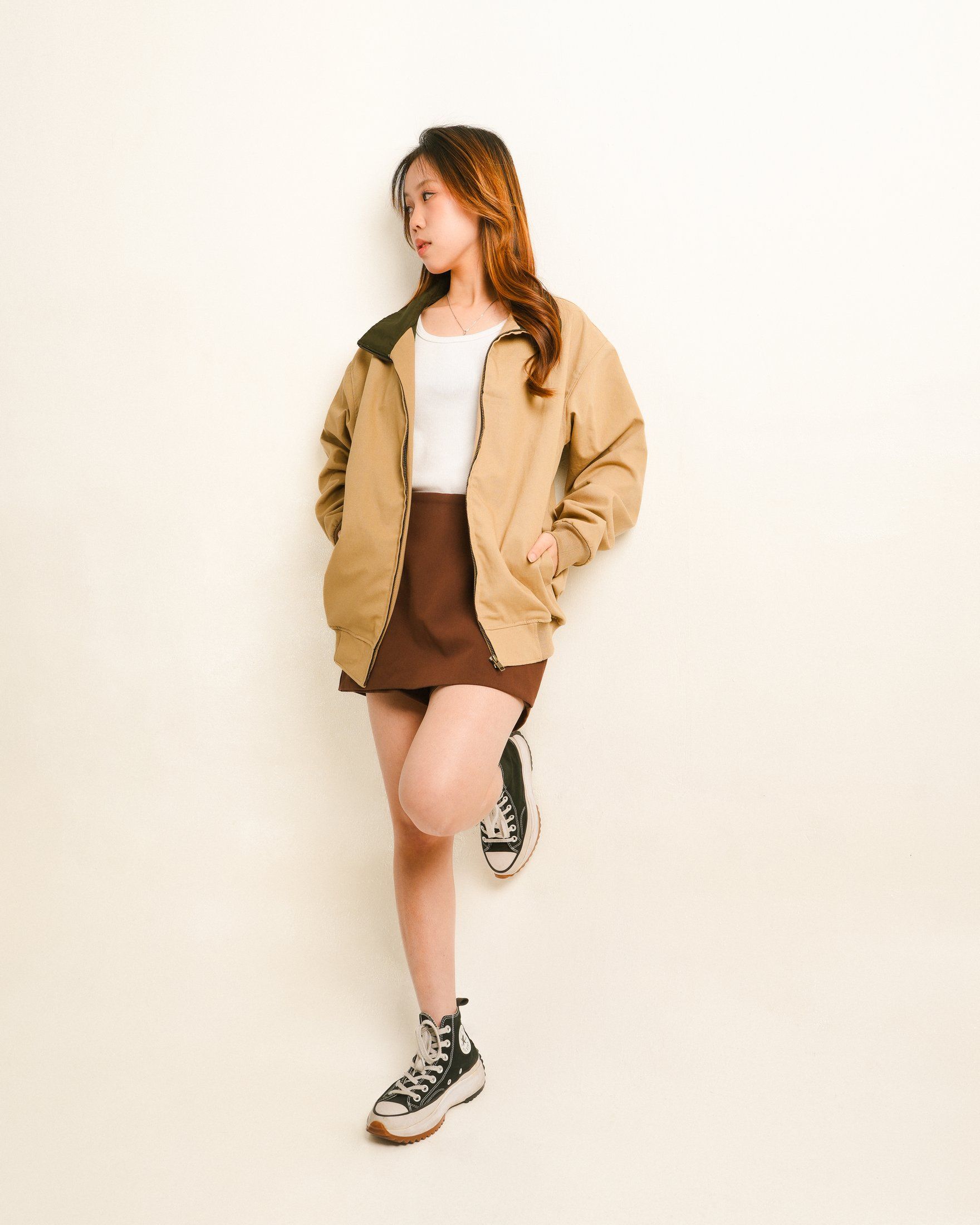 Khaki zipper jacket worn open, leaning on a wall