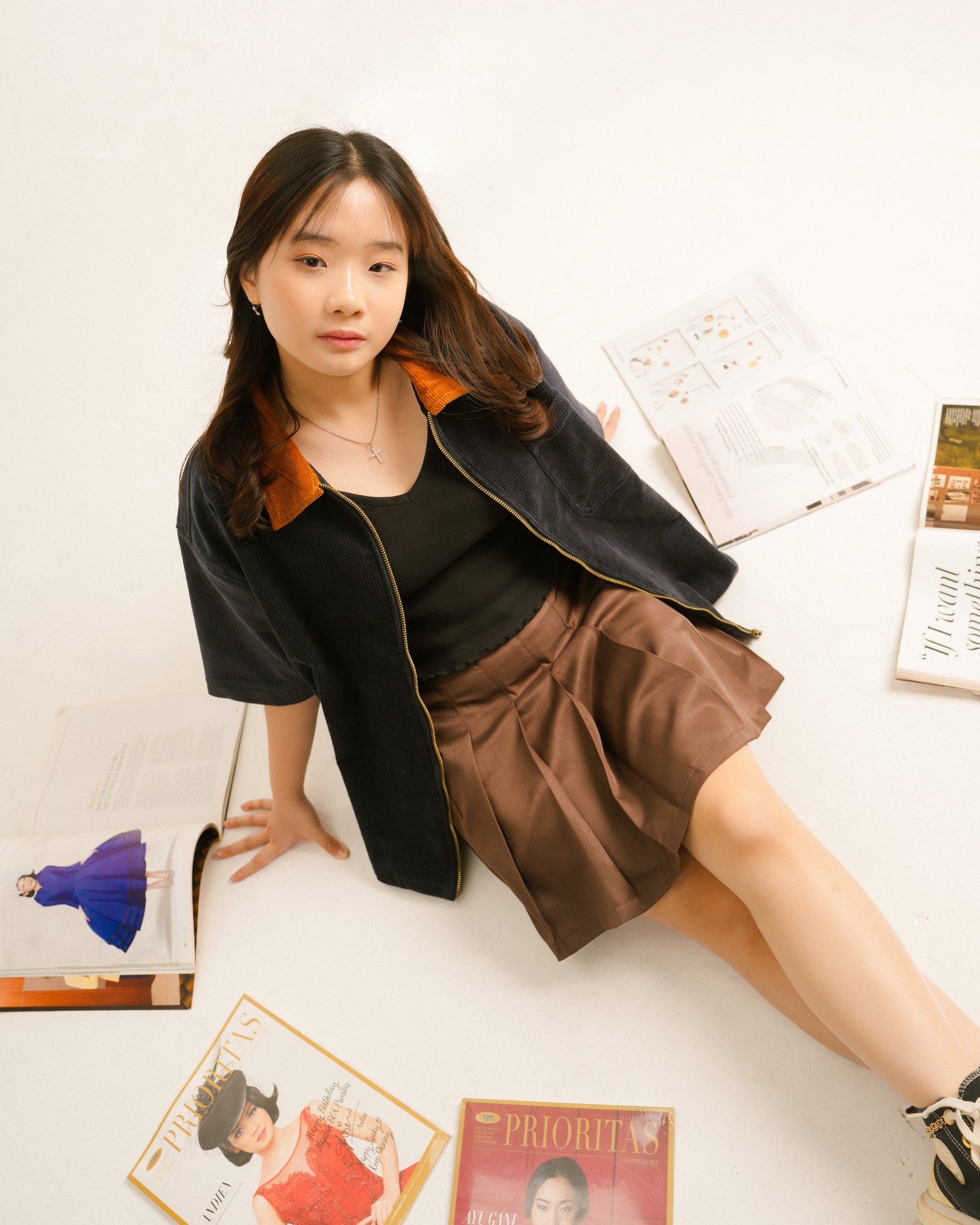 Model sitting on the floor among magazines in the navy workshirt
