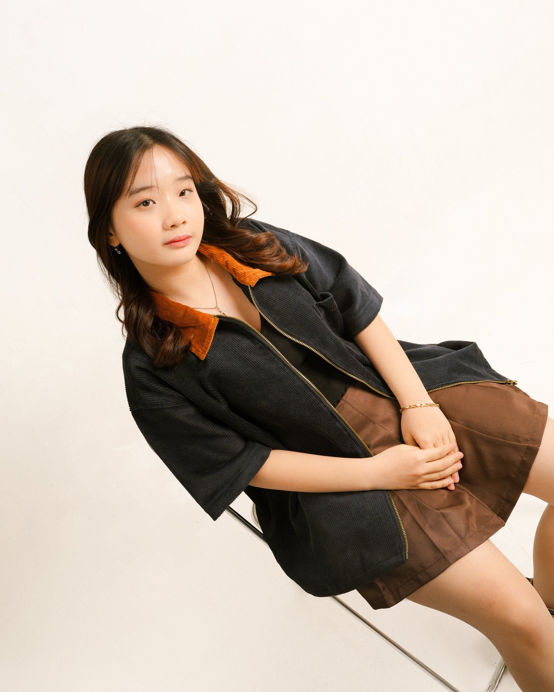 Navy workshirt worn open over a black top and brown pleated skirt