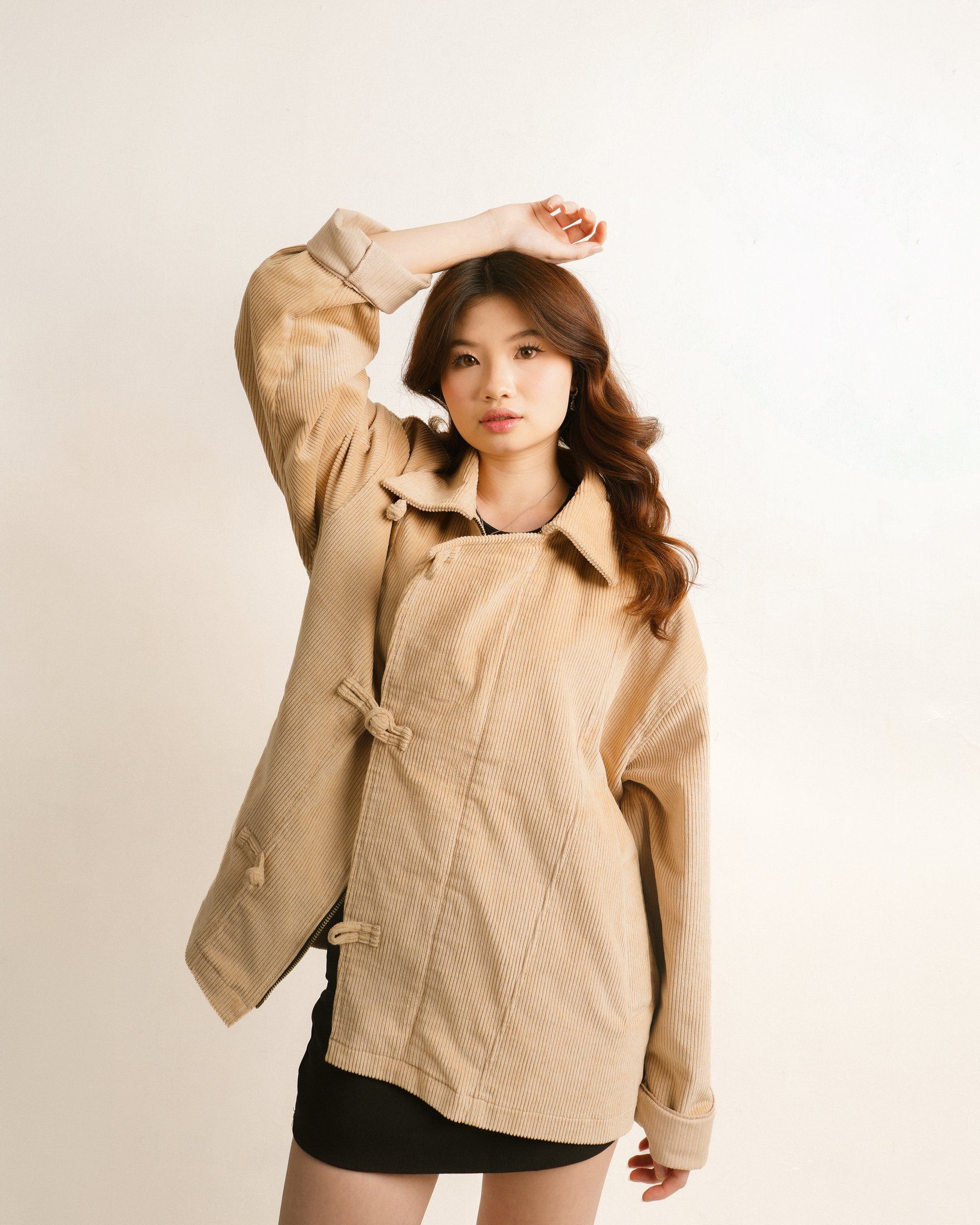 Cream cheongsam jacket worn oversized, one arm raised